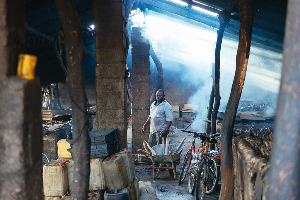 Hombre en el interior e un ahumadero de pescado en la playa de Tanji, Gambia