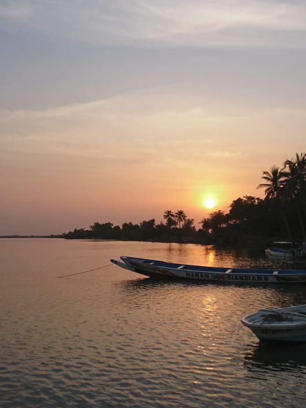 Viajar a Casamance Senegal al atardecer con embarcaciones tradicionales y paisaje tropical